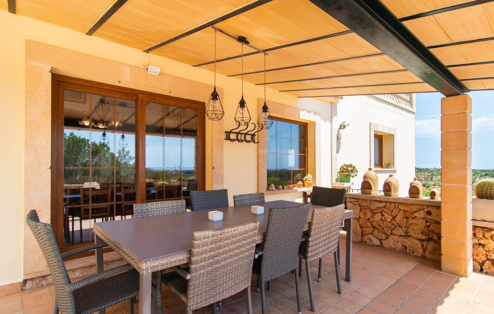 An outdoor dining area with wicker furniture, a pergola, and a stone wall.