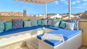 A sunlit outdoor seating area with a blue sofa and patterned cushions, overlooking a coastal town. - Nice home in Arta with private swimming pool, can be inside or outside (Arta)