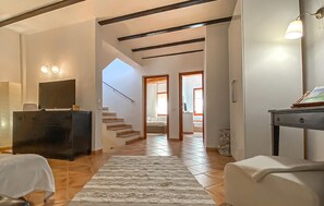 Un hall d’entrée spacieux avec un escalier menant à une chambre, un téléviseur à écran plat et un coin repas comprenant une table et des chaises.
