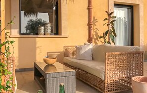 A cozy outdoor seating area with wicker furniture, a wooden table, and a large window providing a view of the outdoors. - Nice home in Campos with private swimming pool, can be inside or outside (Campos)