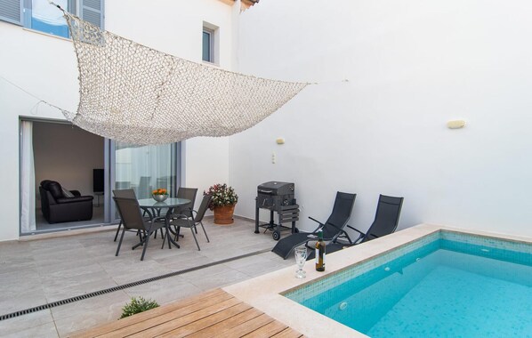 A poolside area with a table and chairs, a barbecue grill, and a pool. - Petit Arta - Sa Botigueta (Arta)