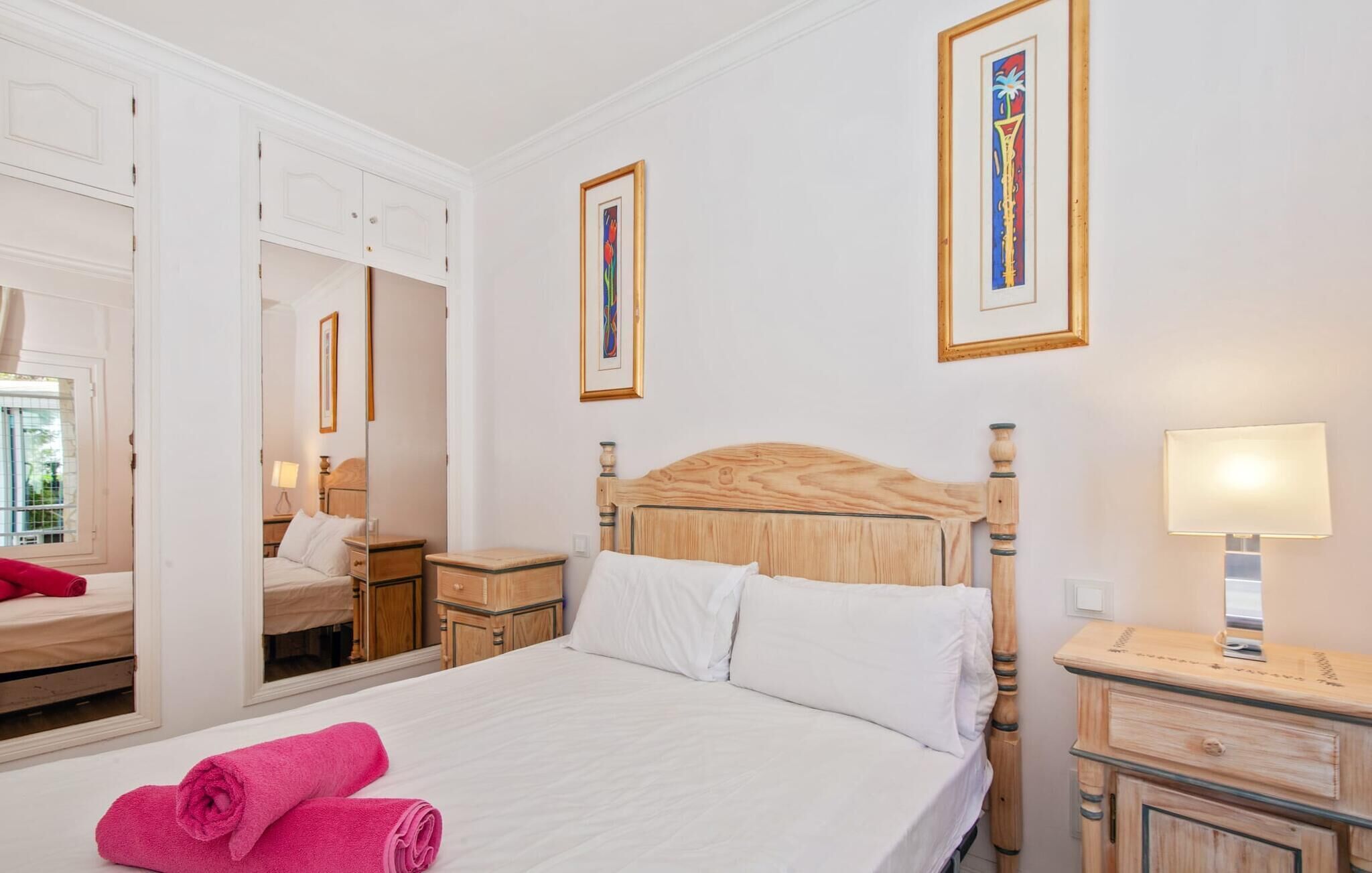 A hotel room with a bed, a nightstand, a mirror, and a wardrobe.