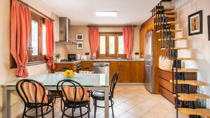 A kitchen with wooden cabinets, a stainless steel refrigerator, a microwave, and a stove. There is a dining table with chairs and a potted plant. - Nice home in Campanet with private swimming pool, can be inside or outside (Campanet)