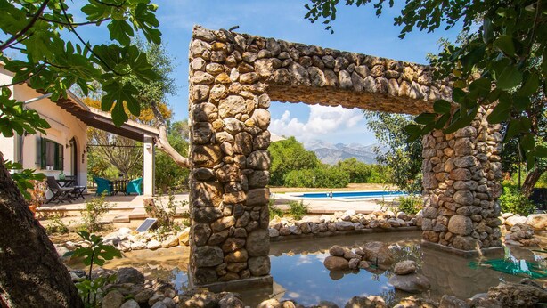 A stone archway leading to a pool area surrounded by rocks and trees. - Nice home in Campanet with private swimming pool, can be inside or outside (Campanet)
