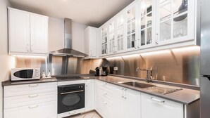Una cucina moderna con mobili bianchi, elettrodomestici in acciaio inossidabile e forno integrato.