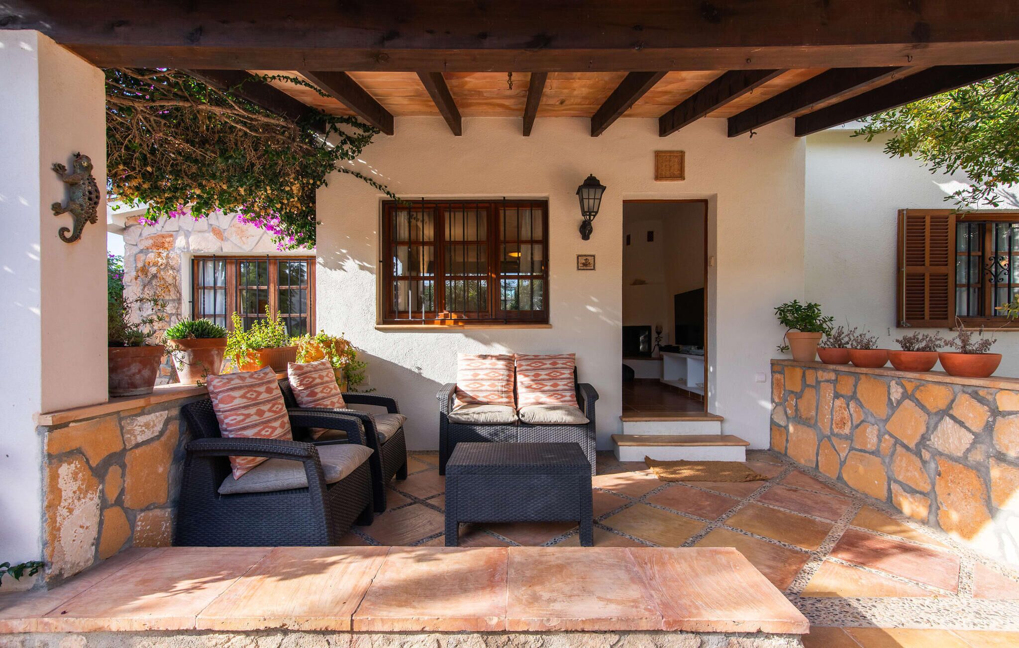 Une terrasse extérieure aménagée avec des meubles en osier, des murs en pierre et des plantes en pot.