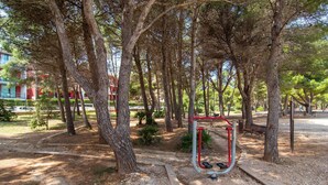 Ein Park mit Bäumen, einem Spielplatz und einem Gebäude im Hintergrund.