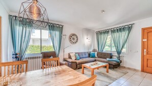 A living room with a wooden dining table, a brown sofa with cushions, a coffee table, and a geometric pendant light. - Gorgeous home in Alcudia with private swimming pool, can be inside or outside (Alcudia)