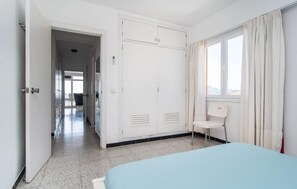 Een hotelkamer met een bed, een stoel, een kledingkast en een raam met gordijnen.