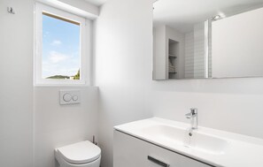 Een moderne badkamer met toilet, wastafel en raam.