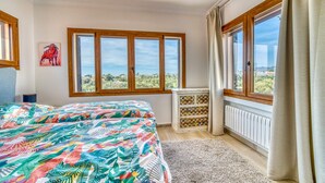 Ein Schlafzimmer mit Bett, einem Fenster mit Blick auf Grünflächen, einem Heizkörper und einem Schrank mit dekorativen Kacheln.