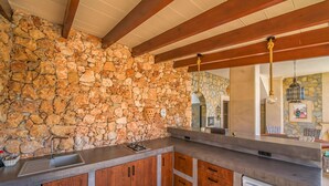 Eine Küche mit Steinwand, Holzschränken, Spüle aus Edelstahl und integriertem Geschirrspüler.