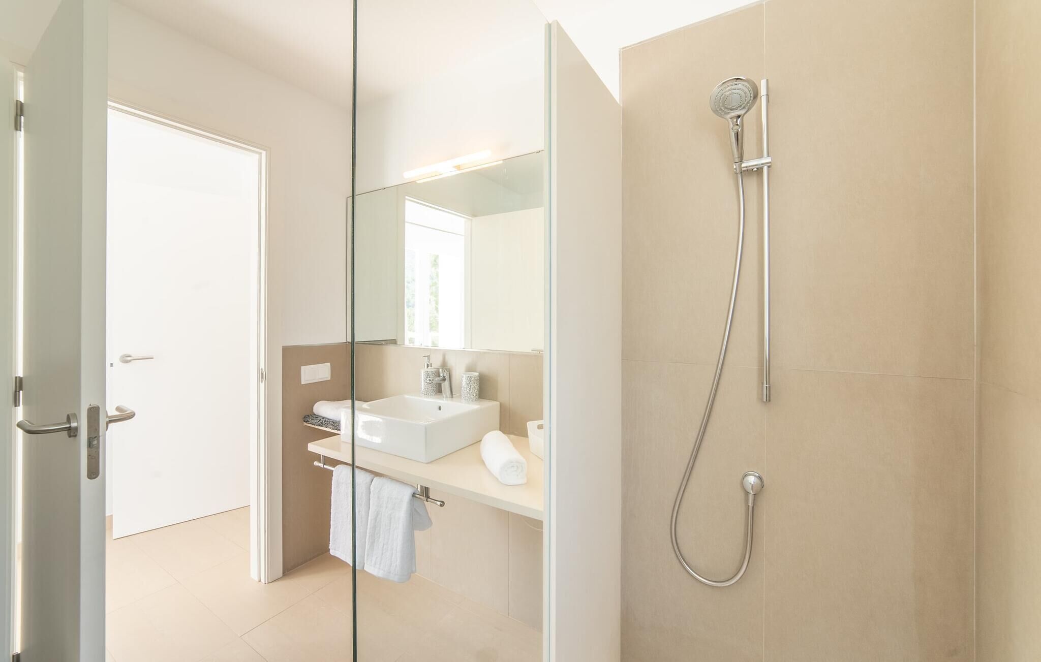 Une salle de bain moderne avec une douche à parois de verre, un lavabo blanc et un miroir.