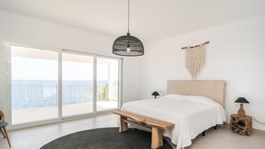 Camera con un'ampia porta scorrevole in vetro che dà su un balcone con vista sul mare.