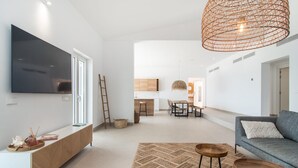 Un soggiorno moderno con televisione a schermo piatto, un divano grigio, un tavolino in legno e un tappeto tessuto.