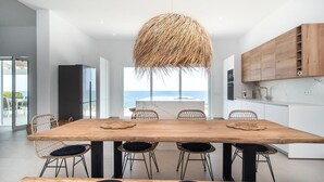 Una cucina moderna con un grande tavolo di legno, sedie in vimini e un lampadario.