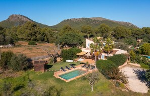 Eine Villa mit Pool, Sitzgelegenheiten im Freien und Blick auf die umliegenden Hügel.