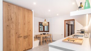 A modern kitchen with a wooden cabinet, a dining area with a table and chairs, and a hanging light fixture. - Lovely home in Alcudia with private swimming pool, can be inside or outside (Alcudia)