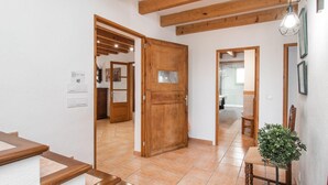 A spacious room with a wooden door, a tiled floor, and a small table with a plant. - Beautiful home in Alcudia with private swimming pool, can be inside or outside (Alcudia)