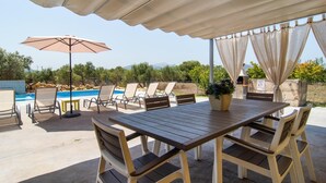 An outdoor patio with a pool, lounge chairs, a wooden table, and a covered area with curtains. - Beautiful home in Alcudia with private swimming pool, can be inside or outside (Alcudia)