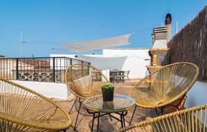 A rooftop terrace with wicker chairs, a glass table, and a white wall. - Nice home in Capdepera with WiFi (Capdepera)