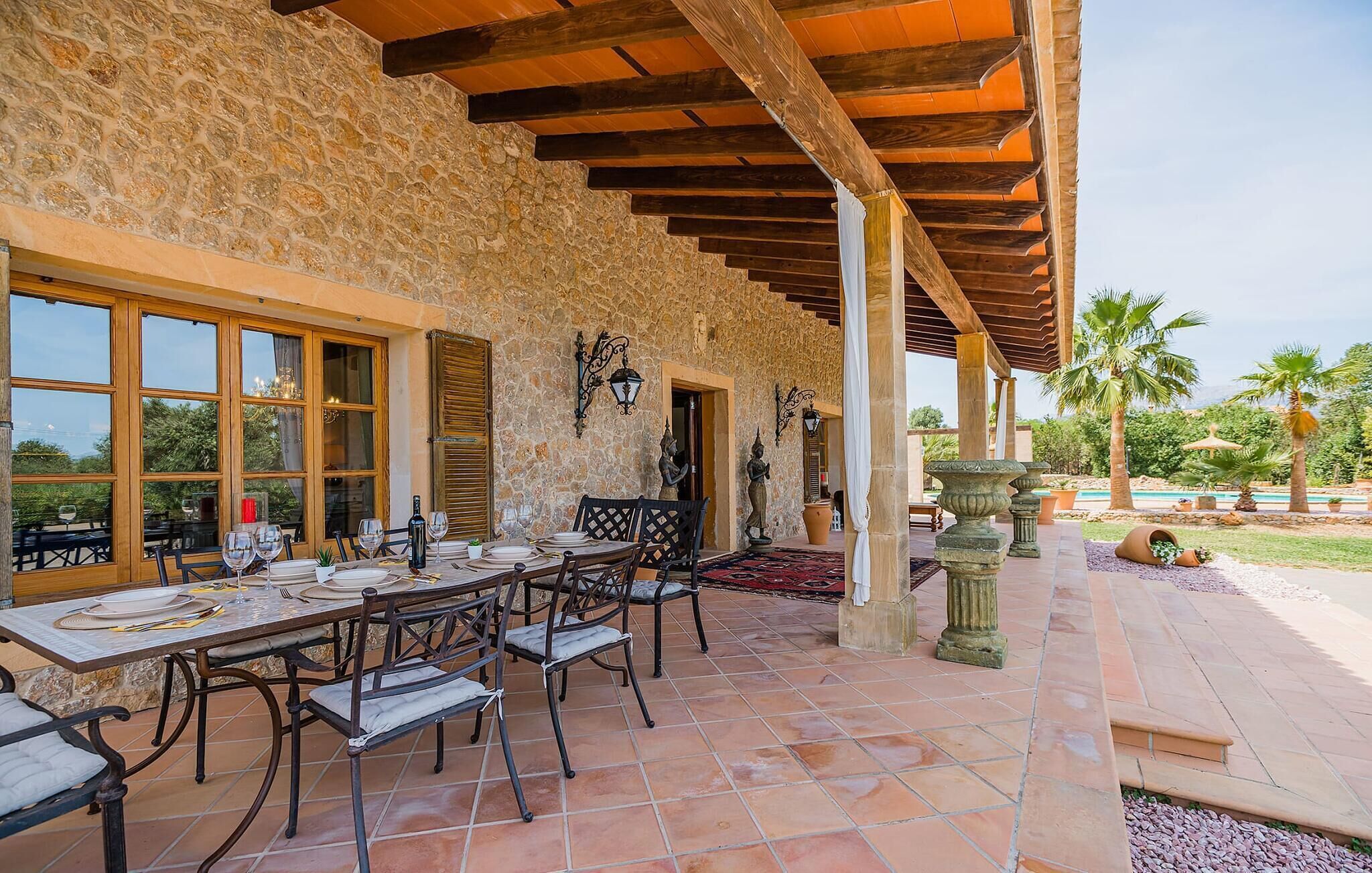Un patio al aire libre con muros de piedra, vigas de madera y una zona de piscina.