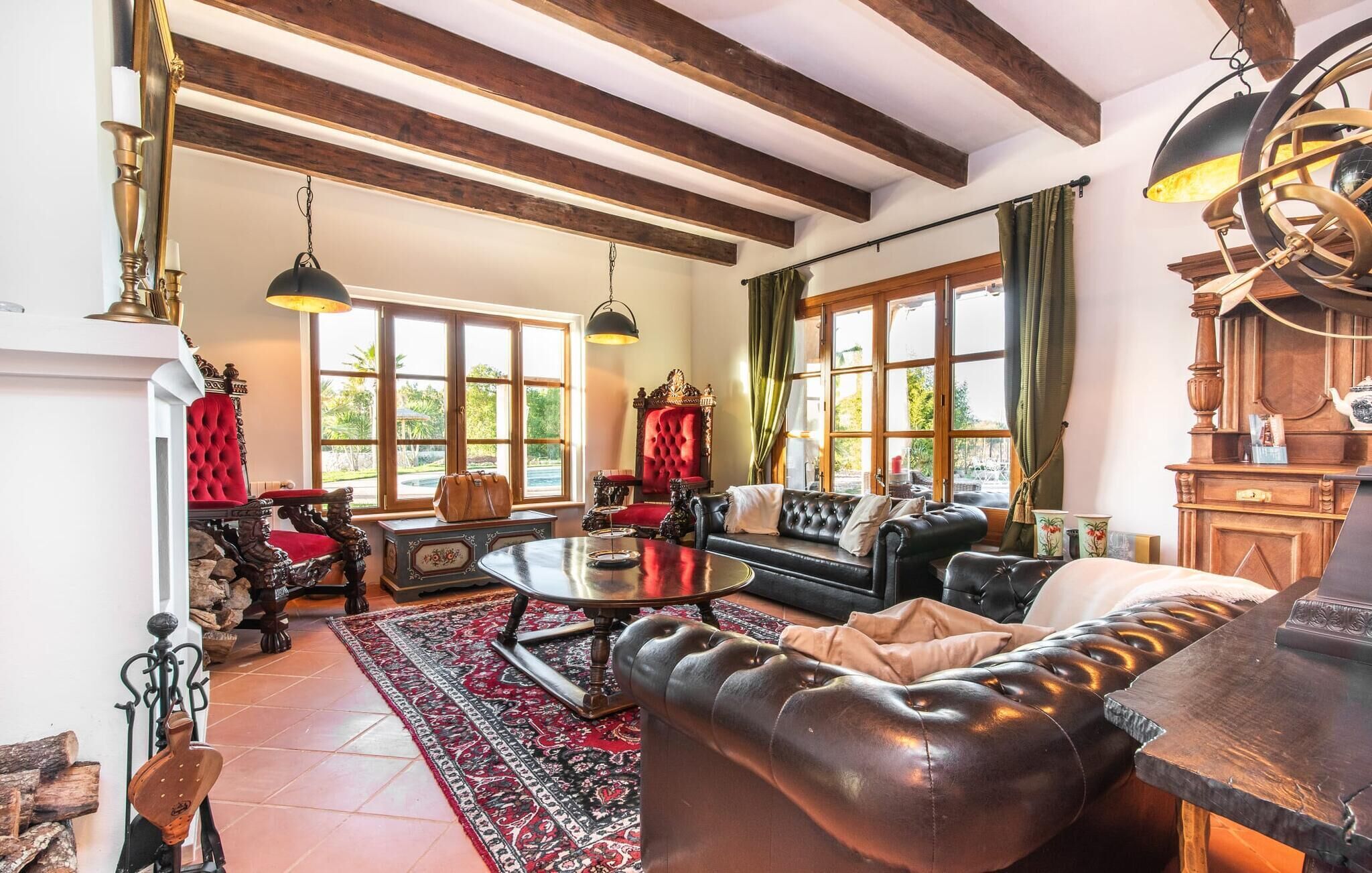 A spacious living room with a high ceiling, large windows, a fireplace, and a leather sofa.