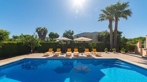 A swimming pool with sun loungers and umbrellas, surrounded by palm trees and a hedge. - Amazing home in Sa Coma with private swimming pool, can be inside or outside (Sa Coma)