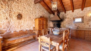 A rustic stone-walled room with a wooden bench, a dining table with chairs, a stone fireplace, and a wooden cabinet. - Stunning home in Llucmajor with private swimming pool, can be inside or outside (Llucmajor)