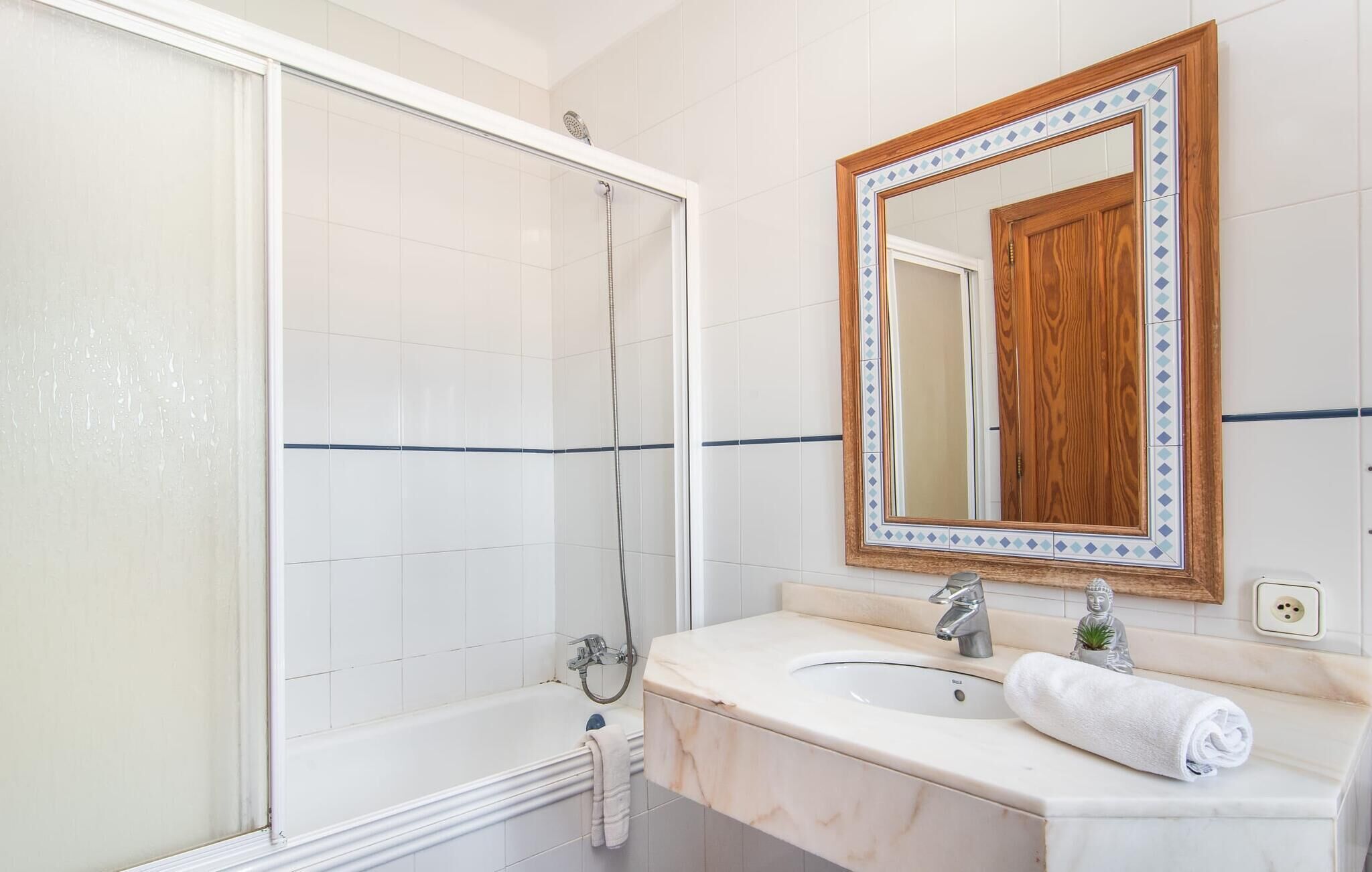 Une salle de bain avec une douche, un lavabo et un miroir.