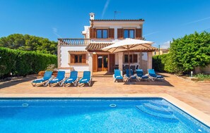 Une villa à deux étages dotée d’une piscine, d’un espace salon extérieur et d’une terrasse couverte.