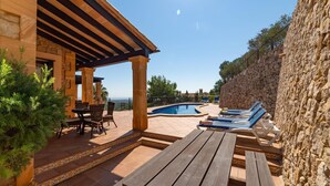A poolside area with a stone wall, wooden pergola, and lounge chairs. - Nice home in Son Macia with private swimming pool, can be inside or outside (Son Macia)