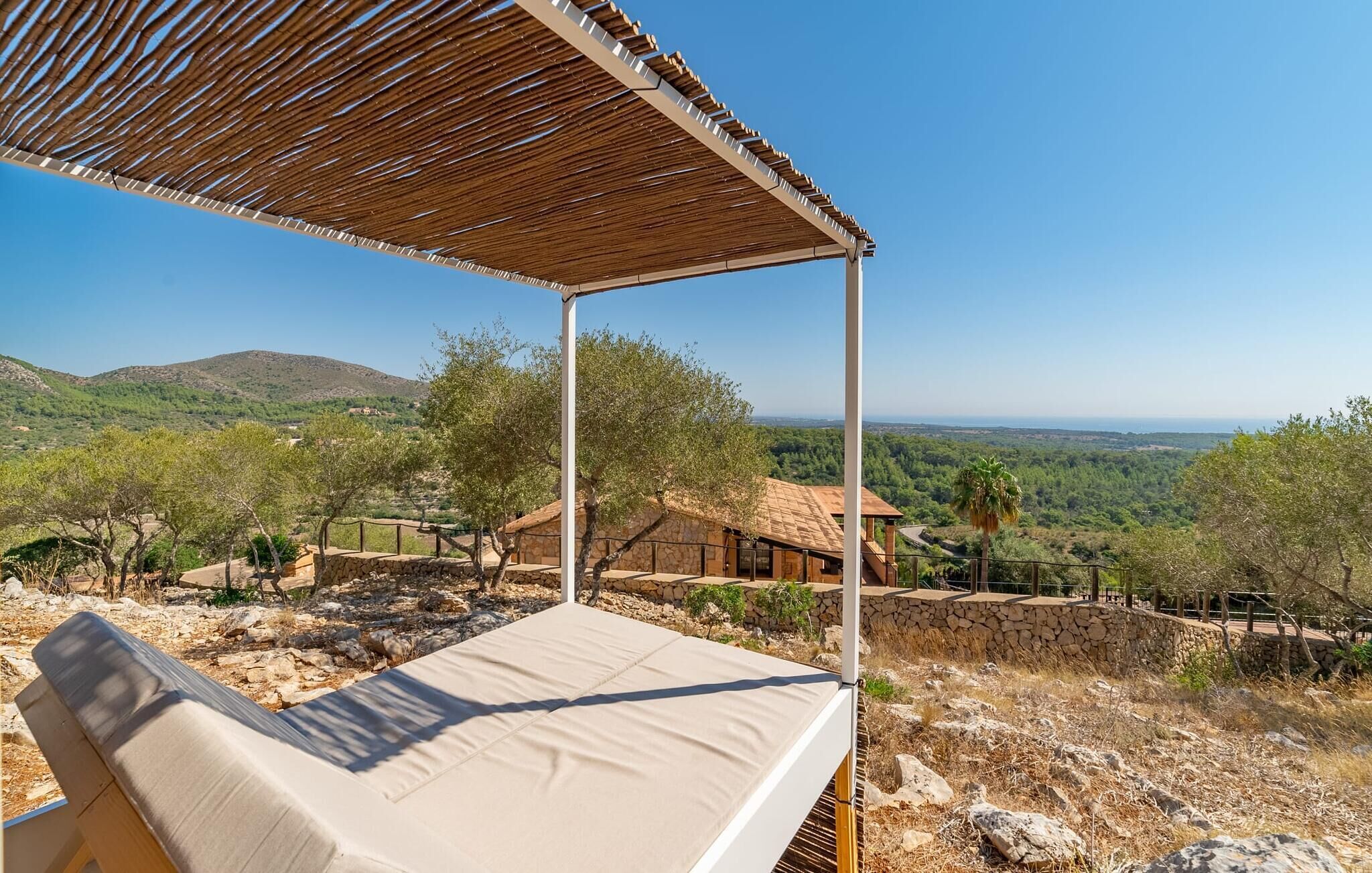 A sunlit outdoor lounge area with a view of a mountainous landscape.
