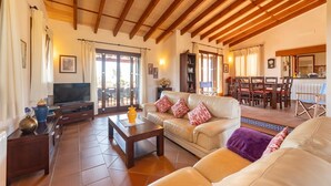 A spacious living room with a wooden ceiling, a television, a sofa, a coffee table, and a dining area with chairs and a table. - Nice home in Son Macia with private swimming pool, can be inside or outside (Son Macia)