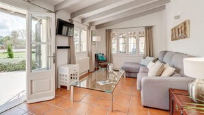 A spacious living room with a glass coffee table, grey sofa, and a TV mounted on the wall. - Lovely home in Pollenca with private swimming pool, can be inside or outside (Pollenca)