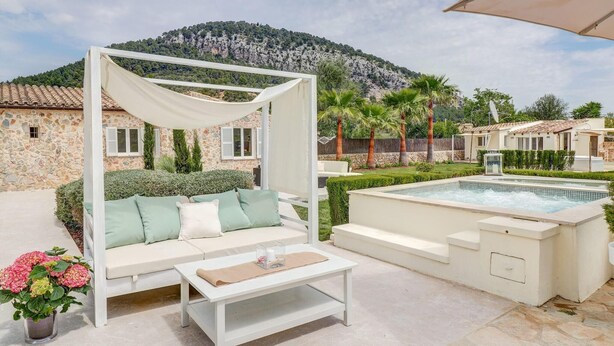 A poolside area with a white outdoor sofa, a table, and a pergola with a white canopy. - Lovely home in Pollenca with private swimming pool, can be inside or outside (Pollenca)