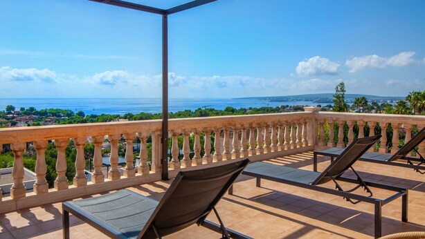 Eine Terrasse mit Meerblick, ausgestattet mit Liegestühlen und einer Pergola.