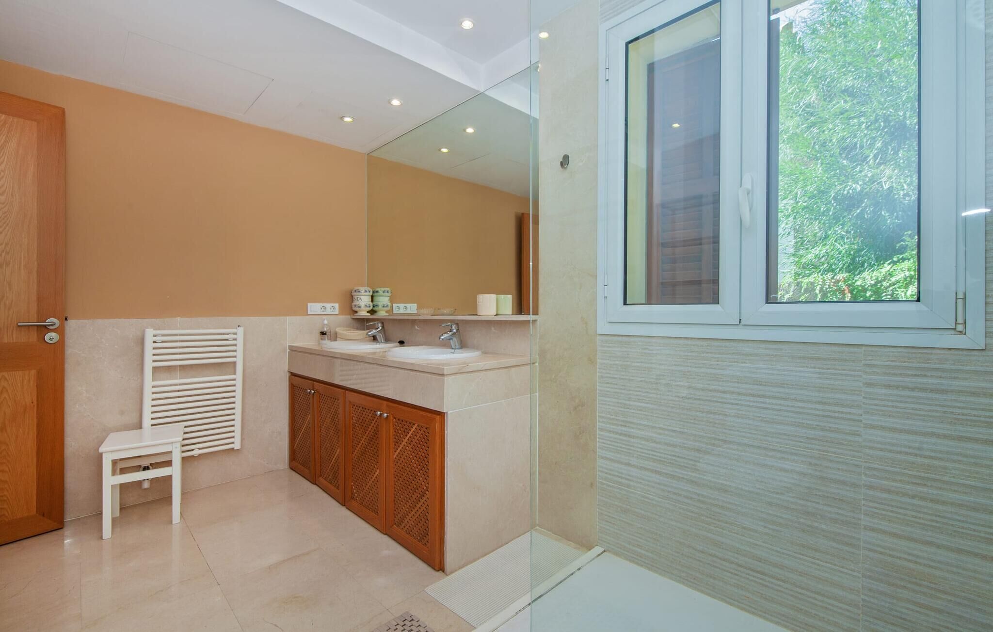A modern bathroom with a large mirror, a sink, and a shower area.