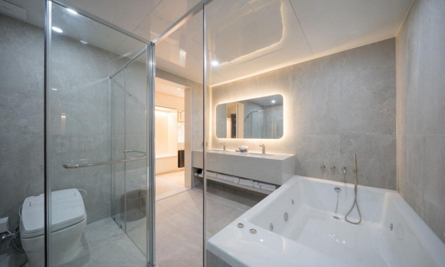 A modern bathroom with a glass shower enclosure, a large bathtub, and a vanity with a mirror.