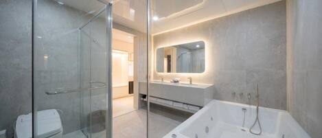 A modern bathroom with a glass shower enclosure, a large bathtub, and a vanity with a mirror.