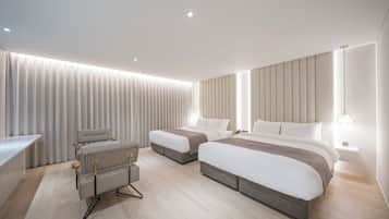 Una habitación de hotel moderna con dos camas, una zona de estar y un escritorio.