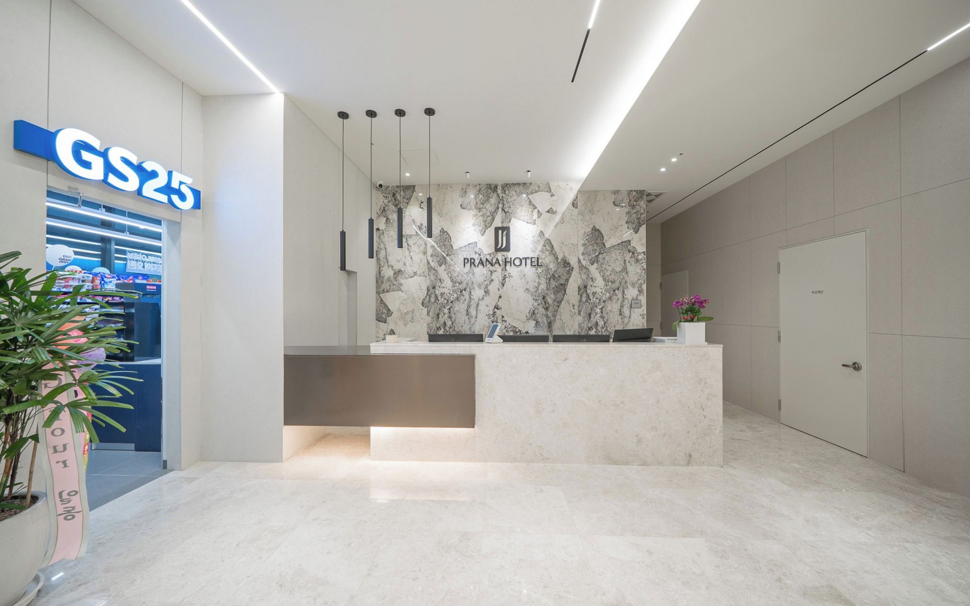 A hotel reception desk with a marble wall and a sign for 'GS25'.