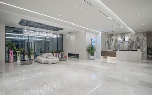 A modern hotel lobby with a reception desk, seating area, and a large window with decorative lights. - Daegu Hyeonpung Prana Hotel (Daegu)