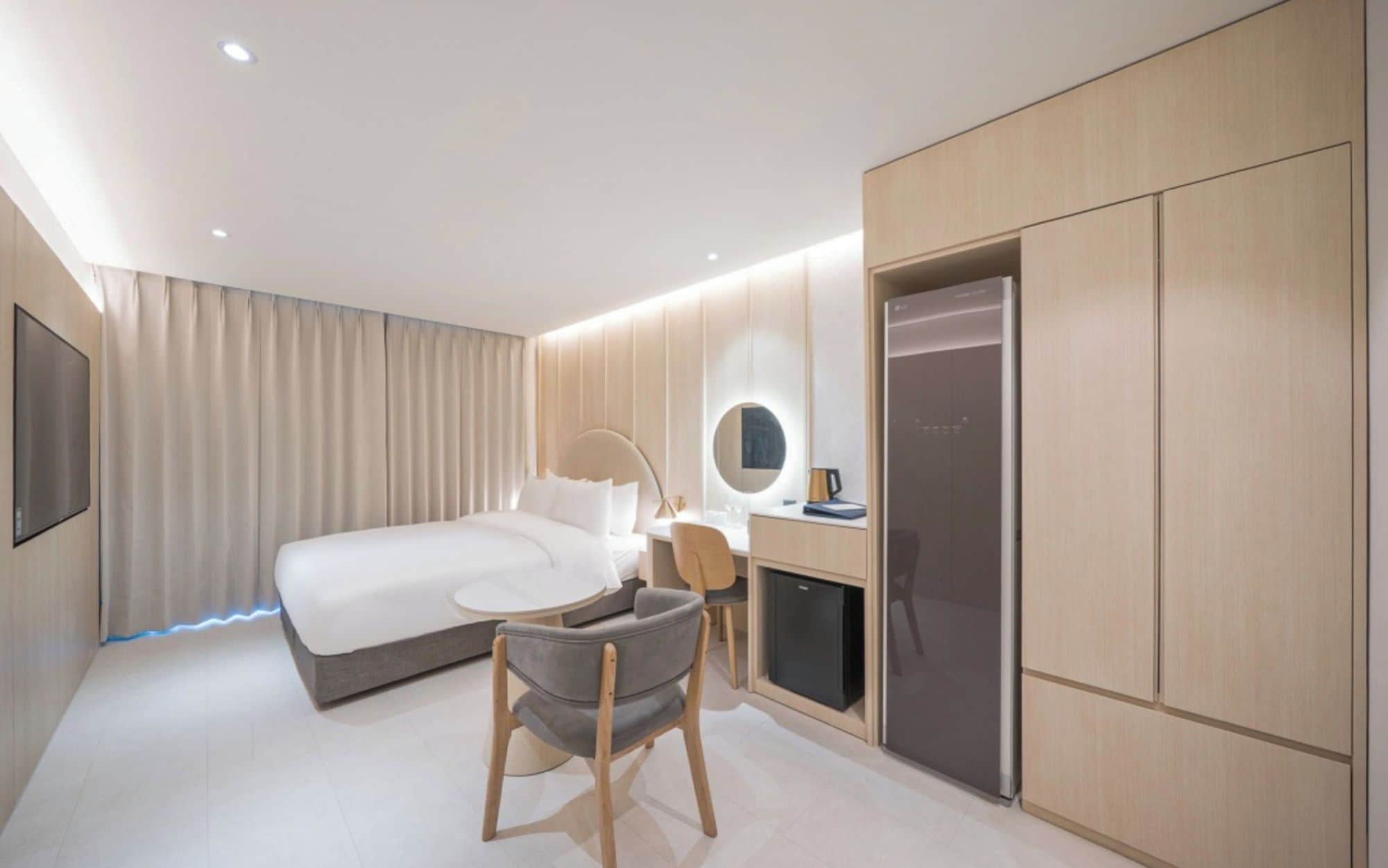 Een moderne hotelkamer met een bed, een bureau, een stoel en een ingebouwde koelkast.