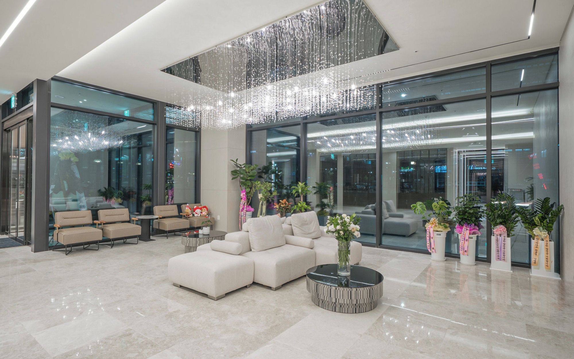 A modern lobby with a seating area, a chandelier, and large windows.