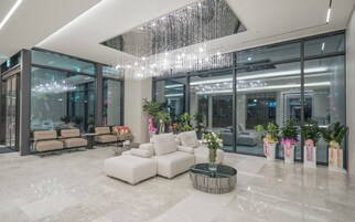 Un vestíbulo moderno con zona de estar, una araña y ventanas amplias.