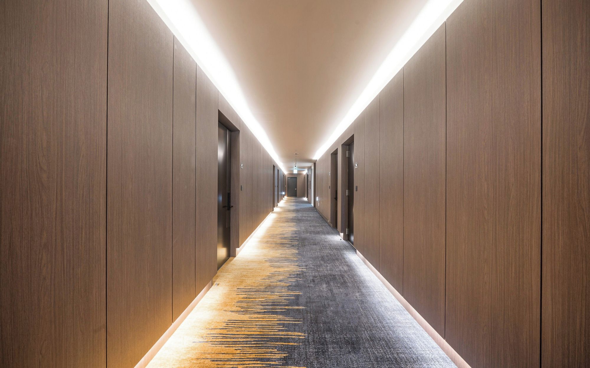 A long, narrow hallway with wooden walls and a carpeted floor.