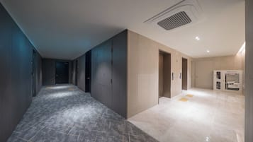 A hallway with a marble floor, a ventilation system, and a vending machine.