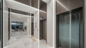 A modern lobby with a glass elevator, a reception desk, and a clear pathway leading to a seating area. - Daegu Hyeonpung Prana Hotel (Daegu)