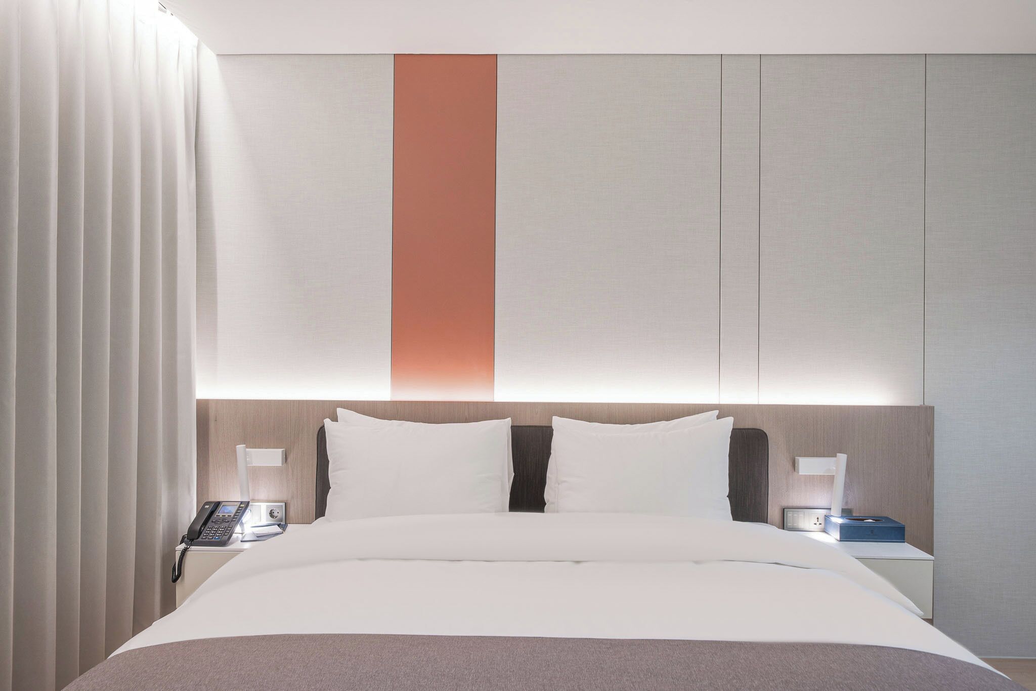 A hotel room with a bed, bedside tables, a phone, and a nightstand.